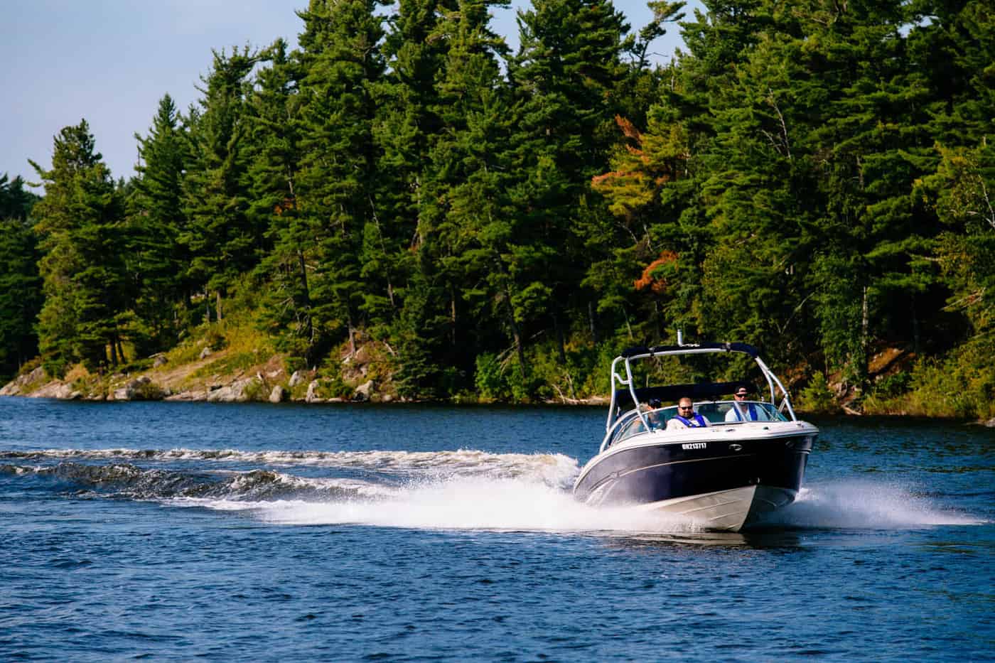 Bowrider boat with three lifejacket-wearing boaters.